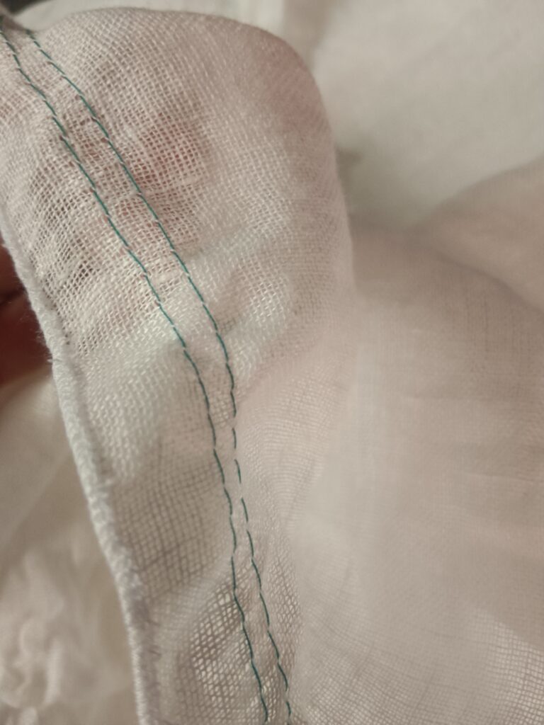 close up der Raffungsnähte in Kontrastfarbe türkis auf weiß